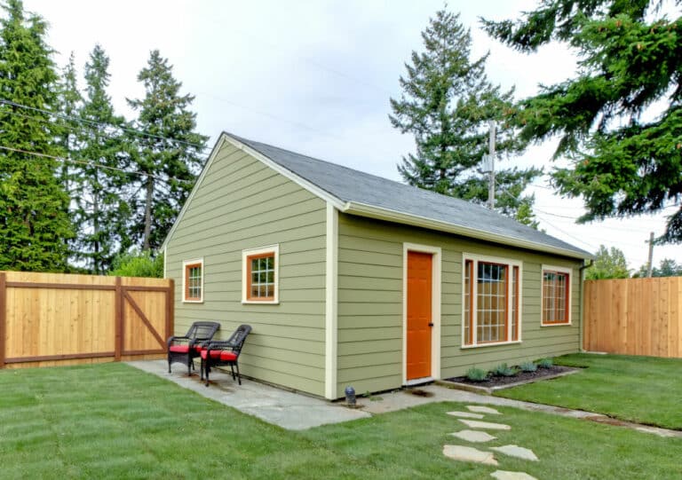 Small green guest houe in the fenced back yard.