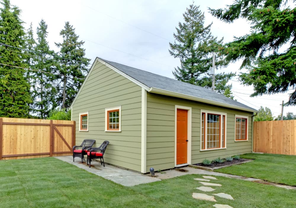 Small green guest houe in the fenced back yard.